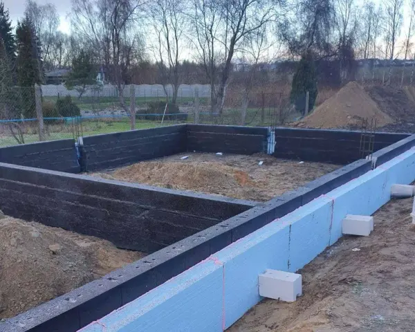 Budowa domu: fundamenty z bloczków fundamentowych i styropianu. Widać zbrojenie i przygotowanie pod wylewanie betonu.