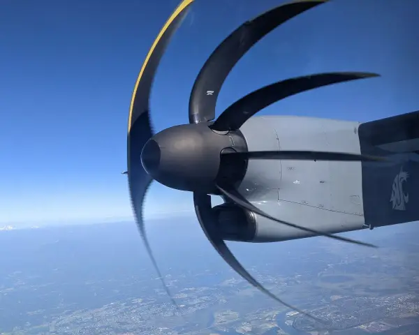 Wirujący śmigłowiec samolotu z efektem rolling shutter nad miastem i górami w oddali.