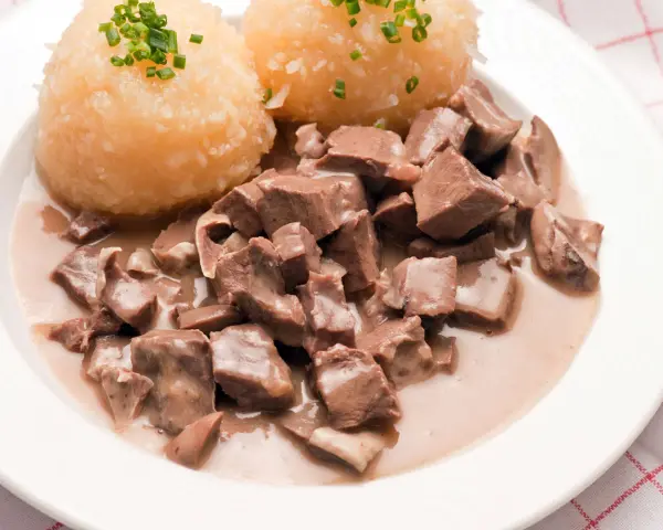 Saure Lunge in cremiger Soße mit Kartoffelklößen, garniert mit Schnittlauch. Ein herzhaftes Gericht, das an Omas Küche erinnert.