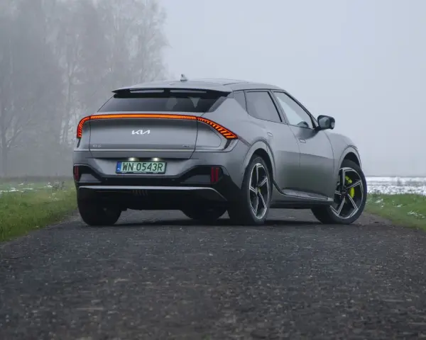 Szare Kia EV6 GT z żółtymi zaciskami hamulcowymi na tle mglistego krajobrazu.