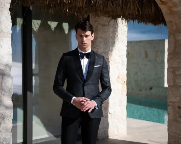 Elegancki mężczyzna w smokingu, idealny przykład stroju black tie na wesele. Różnica między ubiorem black tie a cocktail dress dla gości weselnych jest widoczna.