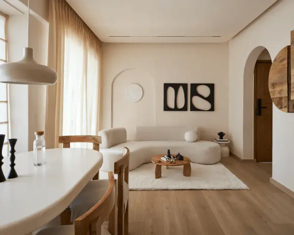 Un soggiorno in stile wabi sabi con divano curvo, tavolino in legno grezzo, tappeto soffice e decorazioni minimaliste.