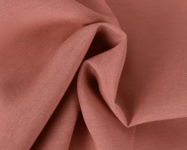 Tessuto twill color salmone, ideale per capi invernali o estivi, con pieghe morbide che ne esaltano la trama.