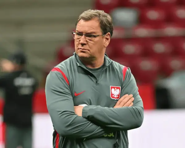 Trener reprezentacji Polski w piłce nożnej, z założonymi rękami, w okularach, zastanawia się, ile zarabia.