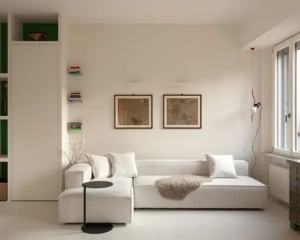 Soggiorno luminoso con divano bianco, quadri antichi e arredi funzionali, perfetto per case piccole ben arredate.