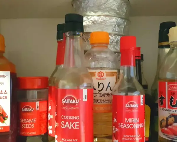 Butelka z napisem "MIRIN SEASONING" obok sosu do sushi i sake. Mirin co to? To japońska przyprawa do gotowania.