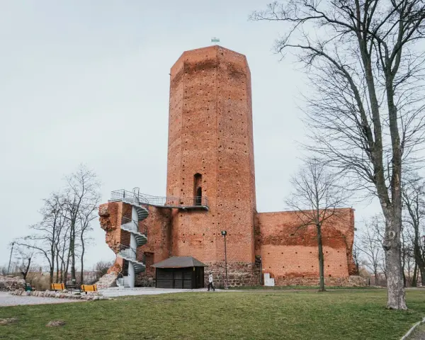 Wysoka, ceglana wieża w mieście, przypominająca mysią wieżę, z kręconymi schodami na zewnątrz.