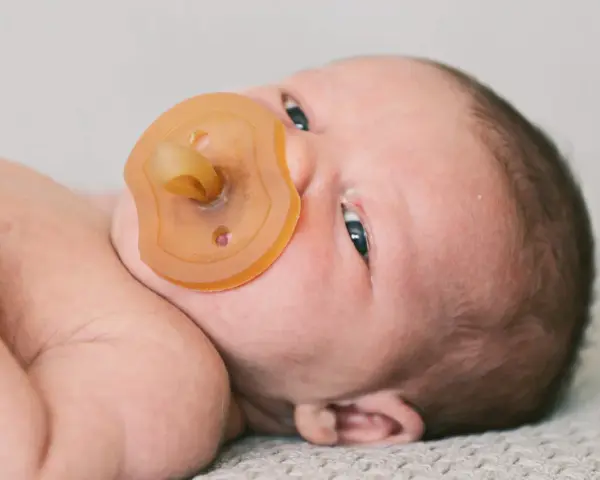 Neugeborenes Baby mit Schnuller. Die Frage "ab wann Schnuller geben" beschäftigt viele Eltern.