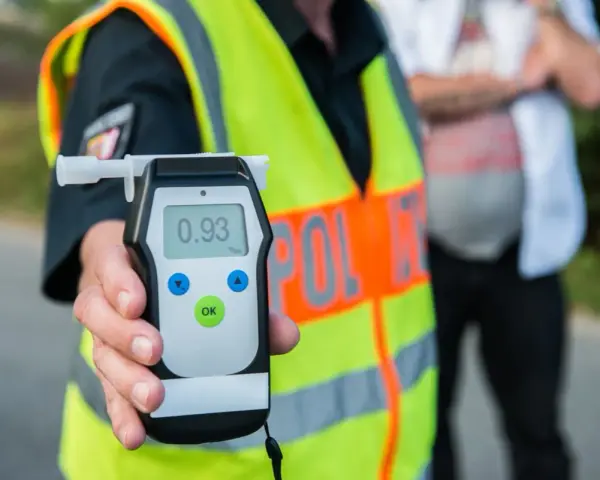 Policjant pokazuje alkomat z wynikiem 0.93 promile alkoholu. Kontrola drogowa trwa.