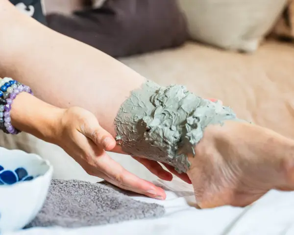 Application d'argile verte sur une jambe, profitant de ses bienfaits détoxifiants et apaisants pour la peau.