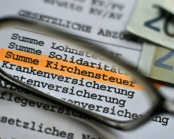 Durch eine Lupe wird die "Summe Kirchensteuer" auf einem Dokument hervorgehoben. Dies zeigt, wo Kirchensteuer anfällt.