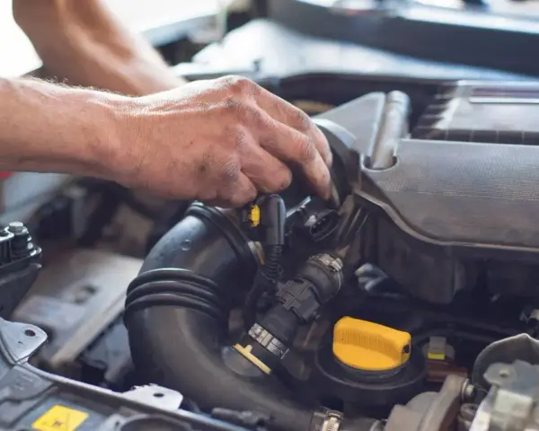 Mechanik pracuje przy silniku, regulując układ dolotowy.