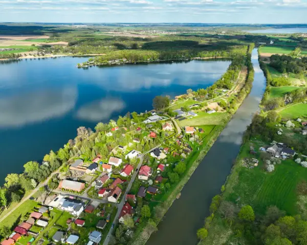 Pławniowice jezioro otoczone zielenią i domkami letniskowymi, z kanałem wodnym biegnącym wzdłuż brzegu.