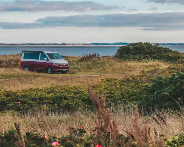 Husbil parkerad vid en kustväg i Danmark, redo för ett äventyr. En perfekt roadtrip danmark-upplevelse.