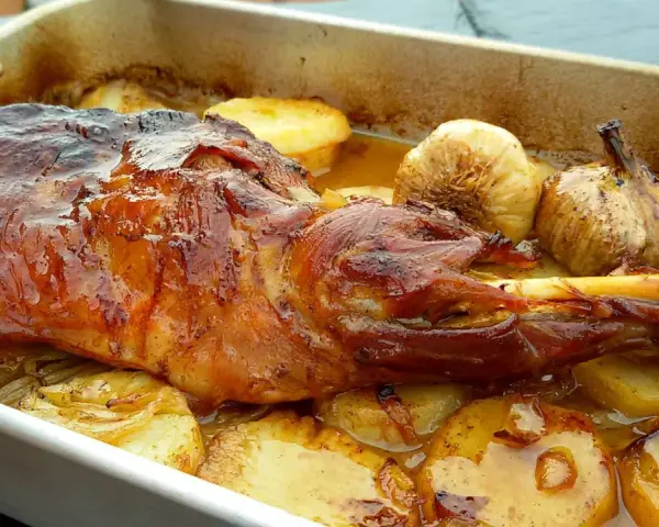 Paletilla de cordero asada al horno con patatas y ajos.