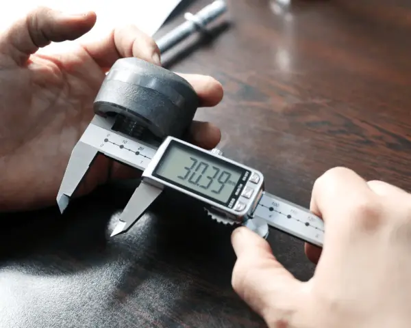 Precyzyjne pomiary: jak mierzyć suwmiarką cyfrową element metalowy, odczyt 30.39 mm.