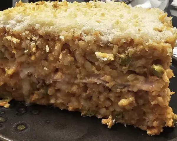 Una fetta di riso al forno, stratificato e dorato, con una crosta croccante di pangrattato.