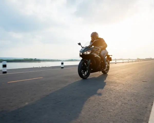 Motocyklista przemierza malownicze trasy motocyklowe pomorskie w blasku zachodzącego słońca.