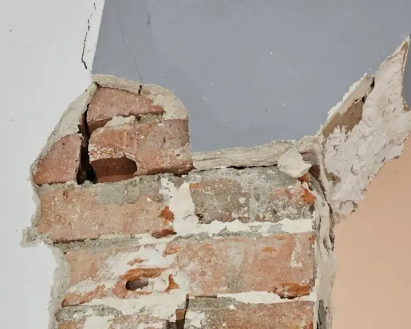 Fissures dans un mur de briques, signe d'une **stabilisation fondation maison sol argileux** nécessaire.