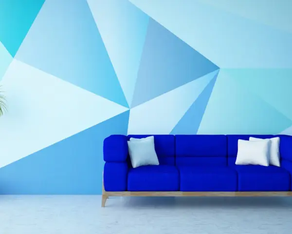 Nowoczesny salon z niebieską kanapą i geometrycznymi wzorami na ścianie malowanymi farbą.