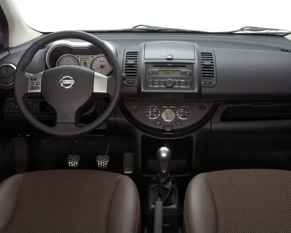 Wnętrze Nissan Note E11: kierownica, deska rozdzielcza z radiem i zegarami, dźwignia zmiany biegów, fotele.
