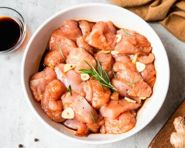 Troceado de pollo marinado con ajo y romero, listo para deliciosas recetas.