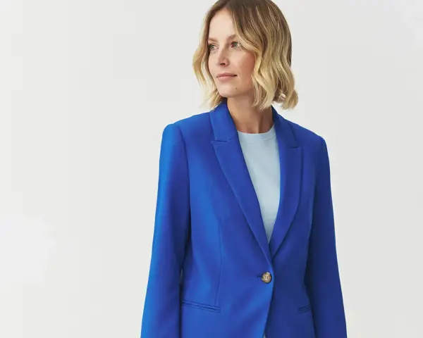 Kobieta w eleganckim, niebieskim żakiecie. Kolor kobaltowy a chabrowy idealnie podkreśla jej urodę.