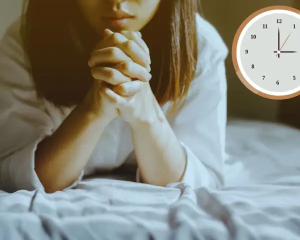 A woman is praying at 3am in the morning, her hands clasped tightly. The clock shows the early hour.