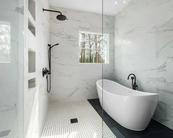 Salle de bain moderne avec baignoire îlot et douche vitrée, murs en porcelaine ou céramique effet marbre.