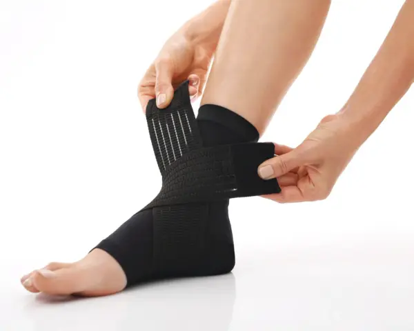 Hands adjust a black compression ankle brace, demonstrating how compression therapy works for support and recovery.