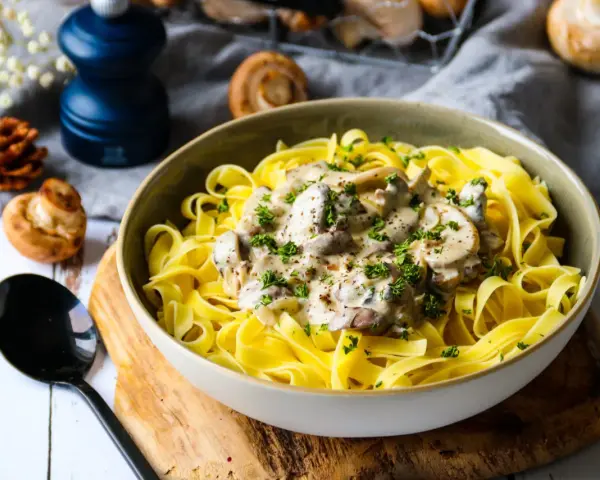 Un plat de pâtes tagliatelles garni d'une onctueuse sauce pour pâtes farcies aux champignons, parsemé de persil frais.