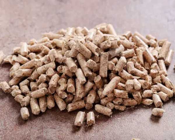 Un mucchio di pellet di abete rosso o bianco, combustibile ecologico per il riscaldamento domestico, su una superficie ruvida.