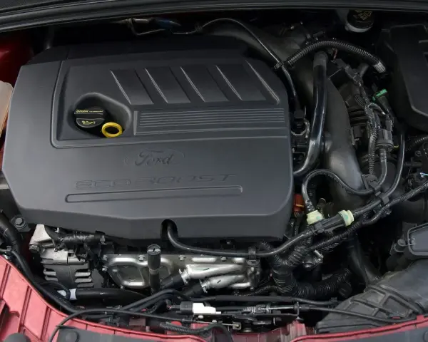 Silniki Ford Focus MK3 EcoBoost. Widok komory silnika z widocznym czarnym plastikowym elementem z napisem "Ford EcoBoost".