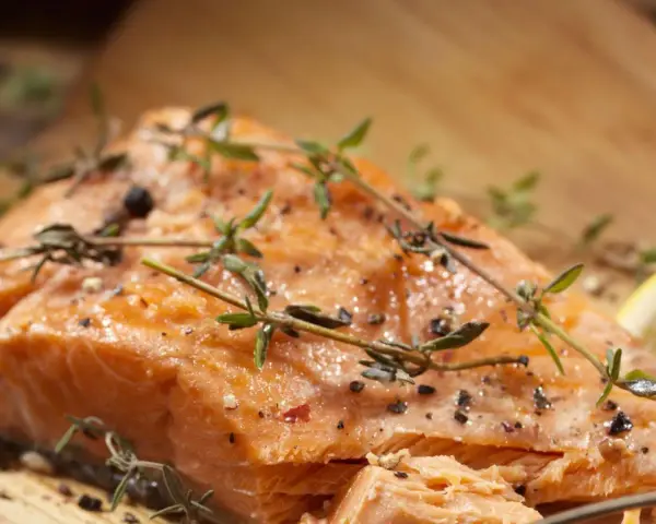 Delicioso salmón al horno, jugoso y dorado, con hierbas frescas y pimienta.