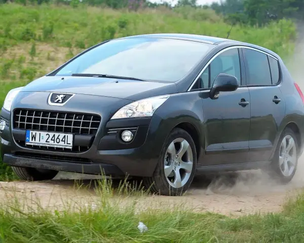 Szary Peugeot 3008 na drodze gruntowej, wzbijający kurz. Wiele osób szuka takich zdjęć, czytając peugeot 3008 opinie forum.