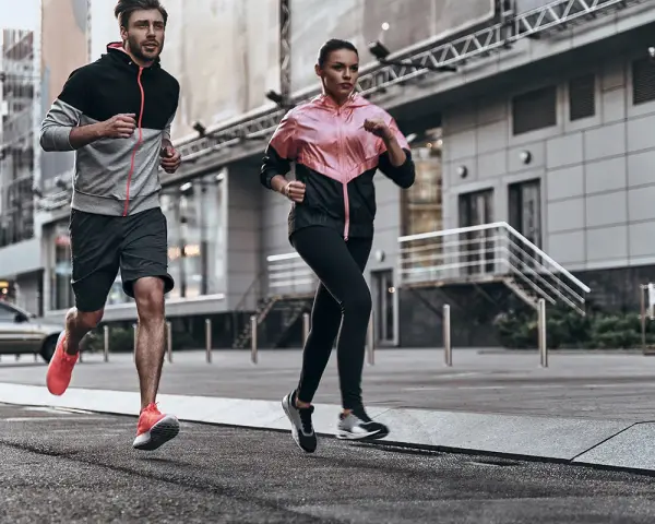 Coppia in corsa running in città, con abbigliamento sportivo colorato.