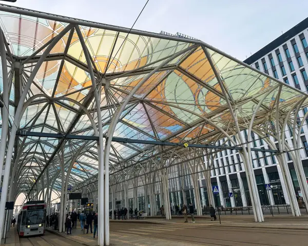 Nowoczesna wiata przystankowa z kolorowym zadaszeniem na ulicy Piotrkowska w Łodzi. Tramwaj czeka na pasażerów.