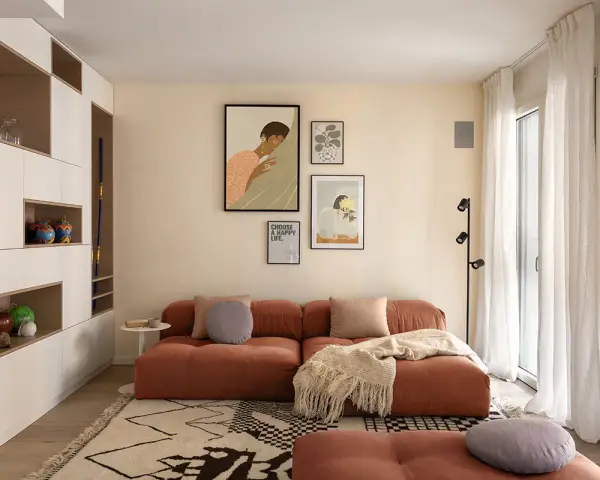 Un soggiorno moderno con divano color terracotta e tappeto geometrico. L'arredamento è pensato per abbinare tappeto e divano, creando un ambiente accogliente.