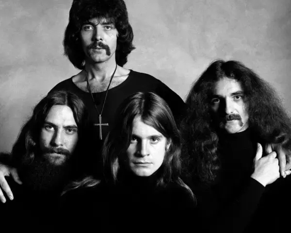 Czarno-białe zdjęcie zespołu Black Sabbath. Czterech mężczyzn z charakterystycznymi fryzurami i wąsami pozuje do portretu.