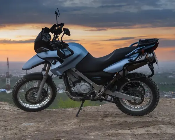 Niebieski motocykl BMW na wzgórzu, gotowy do podróży po Litwie, gdzie obowiązują ograniczenia prędkości.