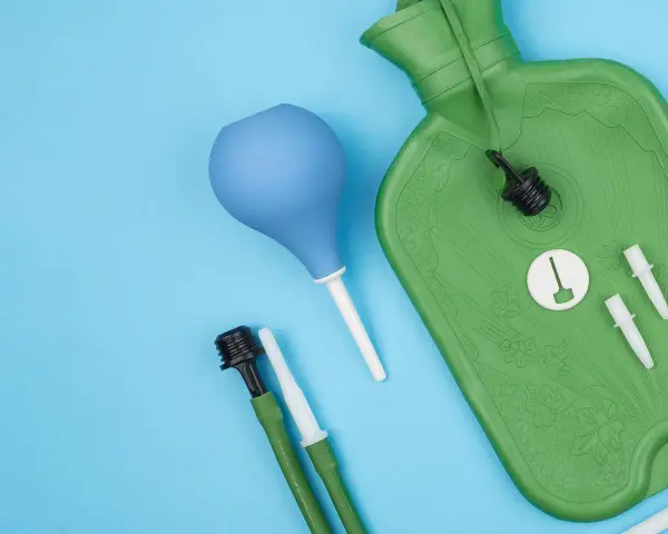 Grüne Spülflasche, blauer Birnensauger und Zubehör für die darmspiegelung vorbereitung auf blauem Hintergrund.