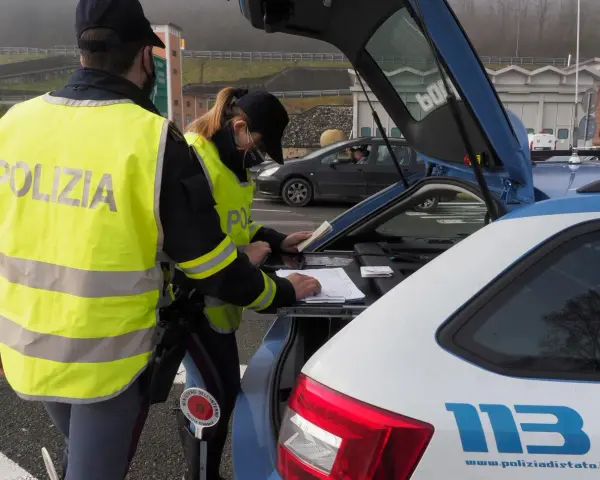 Agenti della Polizia Stradale controllano documenti, forse per un caso di targa clonata, durante un posto di blocco.