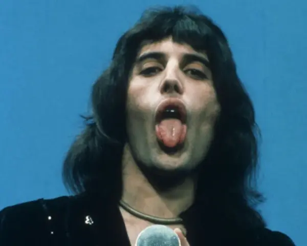 Freddie Mercury z wyciągniętym językiem, śpiewający do mikrofonu. W jego oczach widać pragnienie, by **break free**.