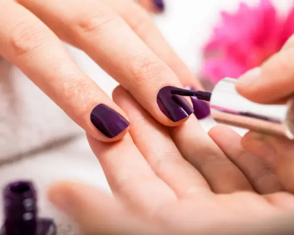Applicazione smalto viola su unghie. Scopri come usare la fibra di vetro per unghie per un look impeccabile.