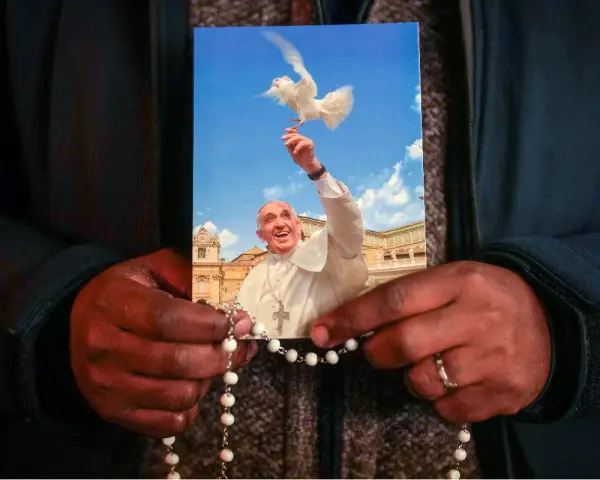 Dłonie trzymają obrazek z Papieżem Franciszkiem wypuszczającym gołębicę. To inspiracja z cytatów papieża franciszka.