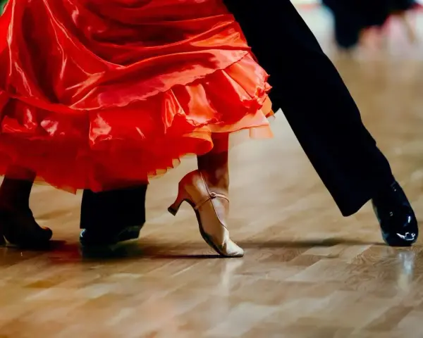 Para tańczy paso doble w rytm muzyki. Czerwona sukienka wiruje, a eleganckie buty poruszają się po parkiecie.
