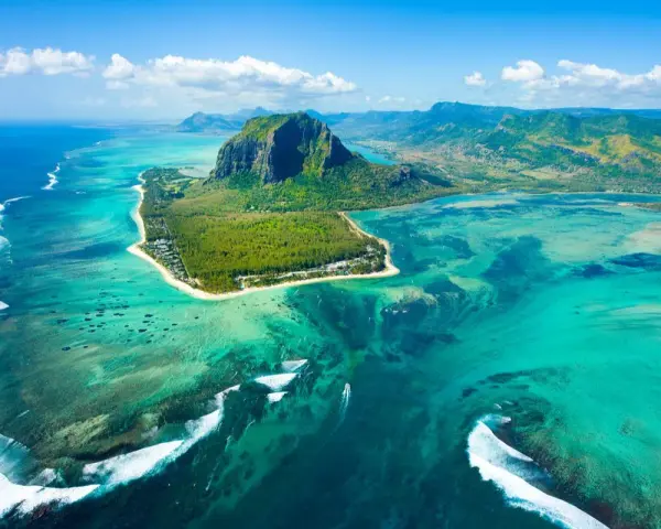 Widok z lotu ptaka na Mauritius: turkusowa laguna, góra Le Morne Brabant i białe fale rozbijające się o rafę. Idealne miejsce na loty na Mauritius.