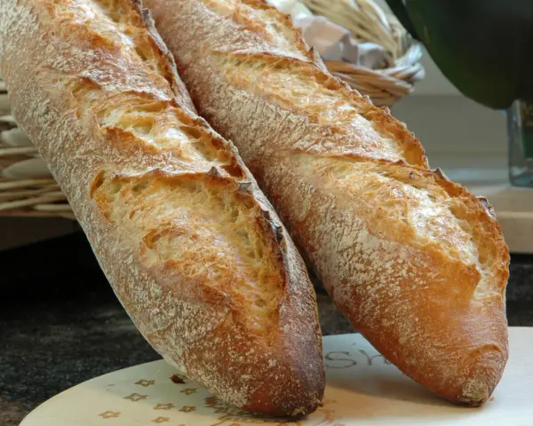 Zwei knusprige Baguettes, eine köstliche t65 Mehl Alternative, liegen auf einem Holzbrett.