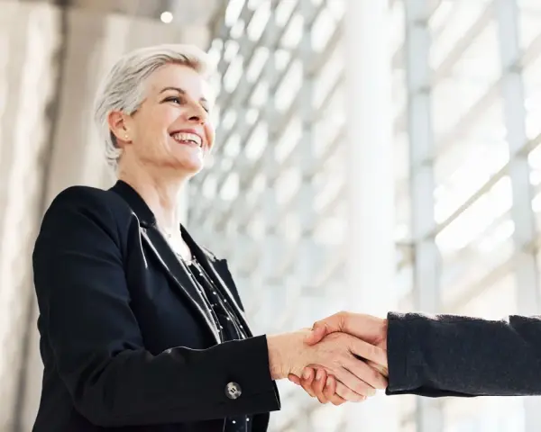 Due professionisti si stringono la mano, un gesto di accordo e fiducia. Sono colleghi raccomandati sul lavoro, pronti a collaborare.