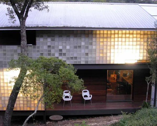 Modern house with a striking glass block installation, bathing the interior in warm light.